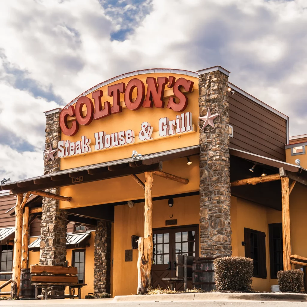 Exterior of Colton’s Steak House & Grill showing a large red sign under a partly cloudy sky—home to Scott Systems' top-tier commercial kitchen ventilation system and restaurant HVAC installation.
