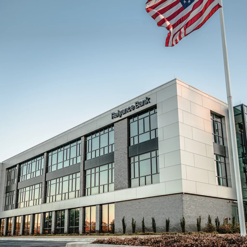 A modern three-story office building with large windows and a sign reading Reliance Bank, which Scott Systems equipped with commercial air conditioning and heating systems.