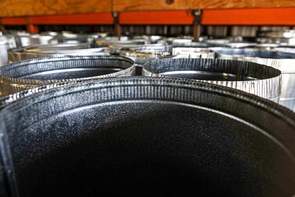 Close-up view of several large, cylindrical metal containers arranged in rows on a shelf in an industrial setting.